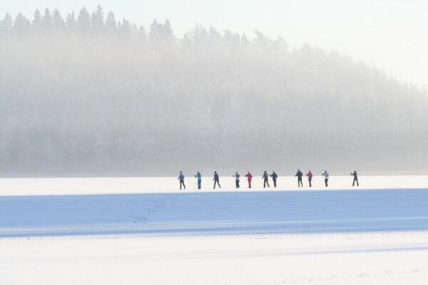 Grupp suusatajaid matkab Otepää Pühajärve jääl üksteise järel, hanereas. On karge külmaga päikseline päev. Matkasuusad loovad unustamatu talveelamuse.