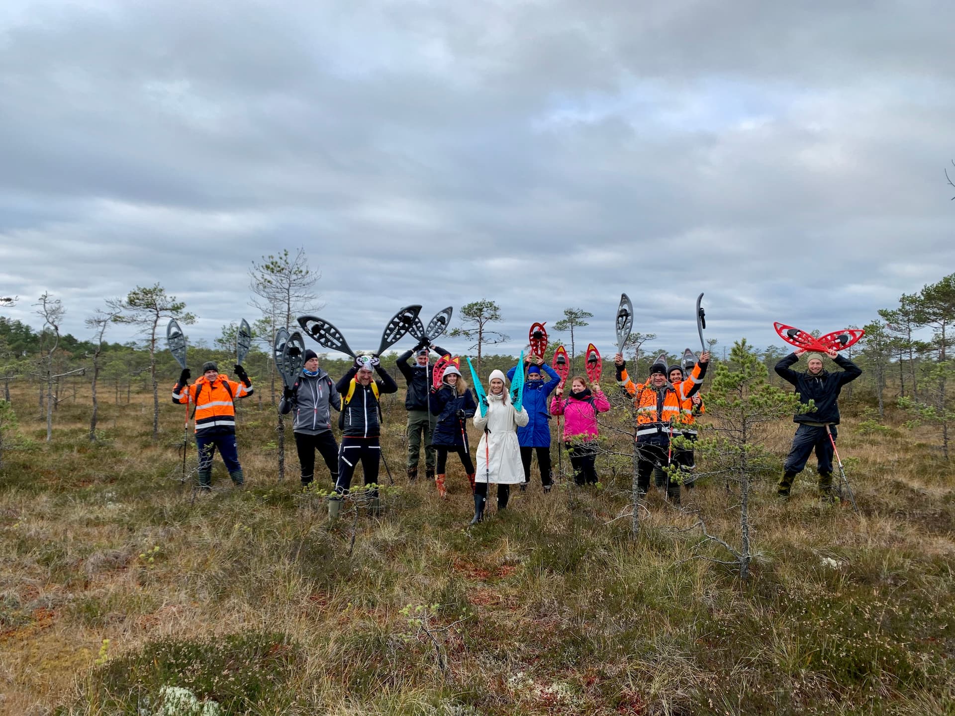 Grupp räätsamatkajaid seisab rabapeenral, räätsad lustlikult tõstetuna jänese kõrvadeks. Räätsamatk Lõuna-Eestis, Rubina soo rabas, MulgiValgama osas.